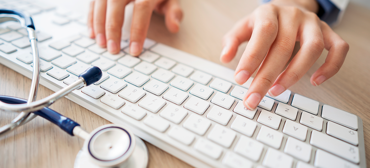 close up of a clinician typing on a computer keyboard
