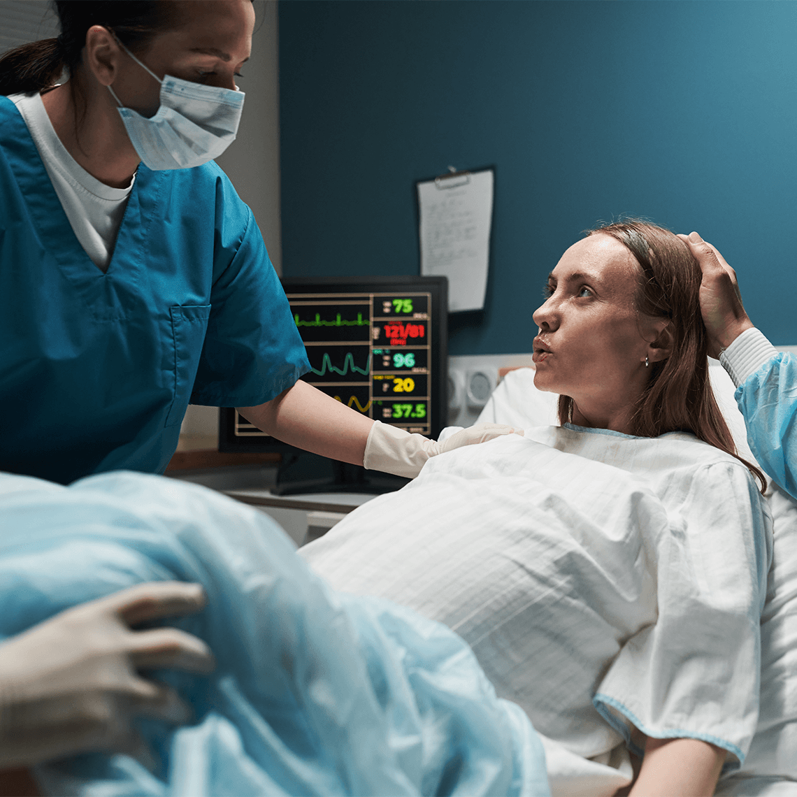 Pregnant female breathing through labor in room with male clinicians in scrubs