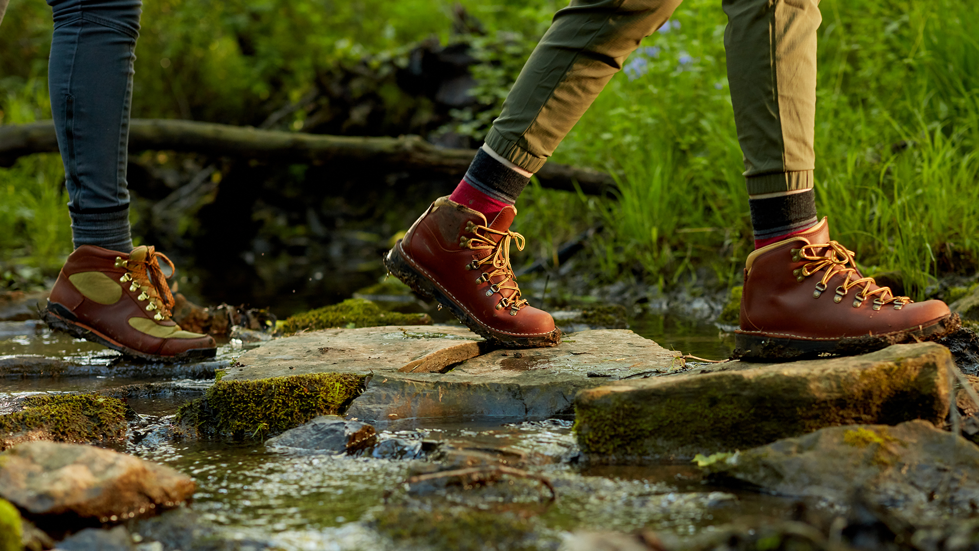 Closeup of hikers crossing a stream on stepping stones