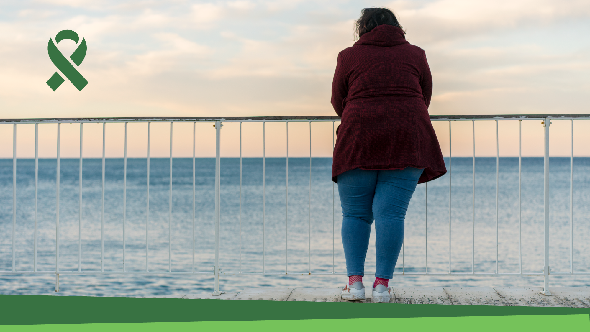 Mental Health Awareness Month. A woman looks out at the ocean with her back to the camera.