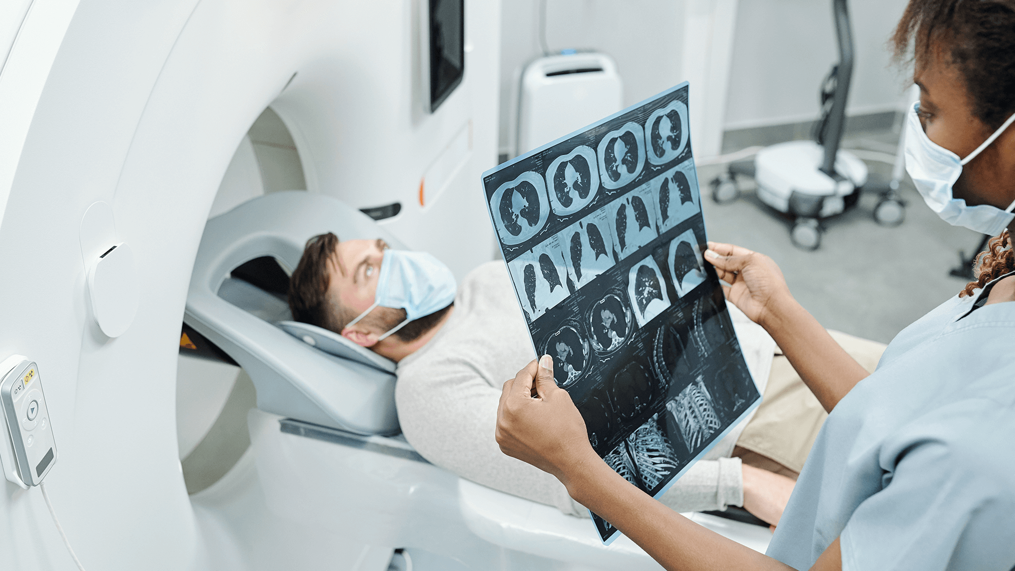 In a hospital gown, a woman holds an MRI scan, examining it closely in a healthcare facility