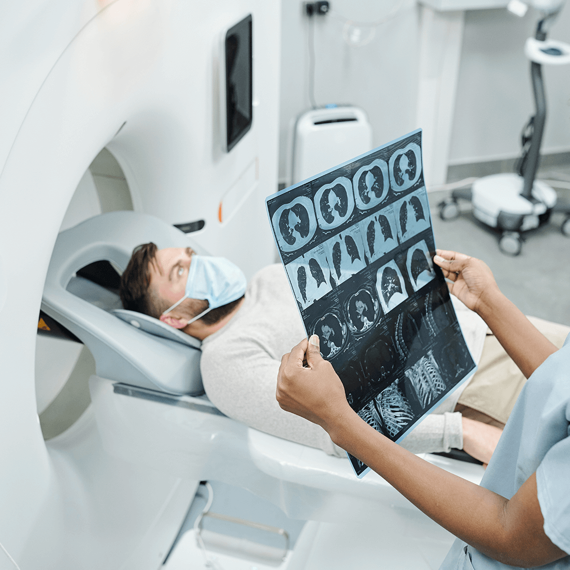 In a hospital gown, a woman holds an MRI scan, examining it closely in a healthcare facility