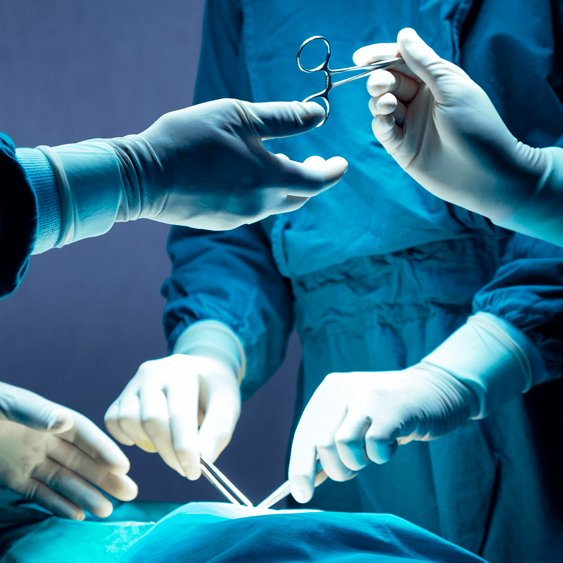 A surgeon conducts a surgical procedure on a patient, with medical equipment and assistants present in the operating theater
