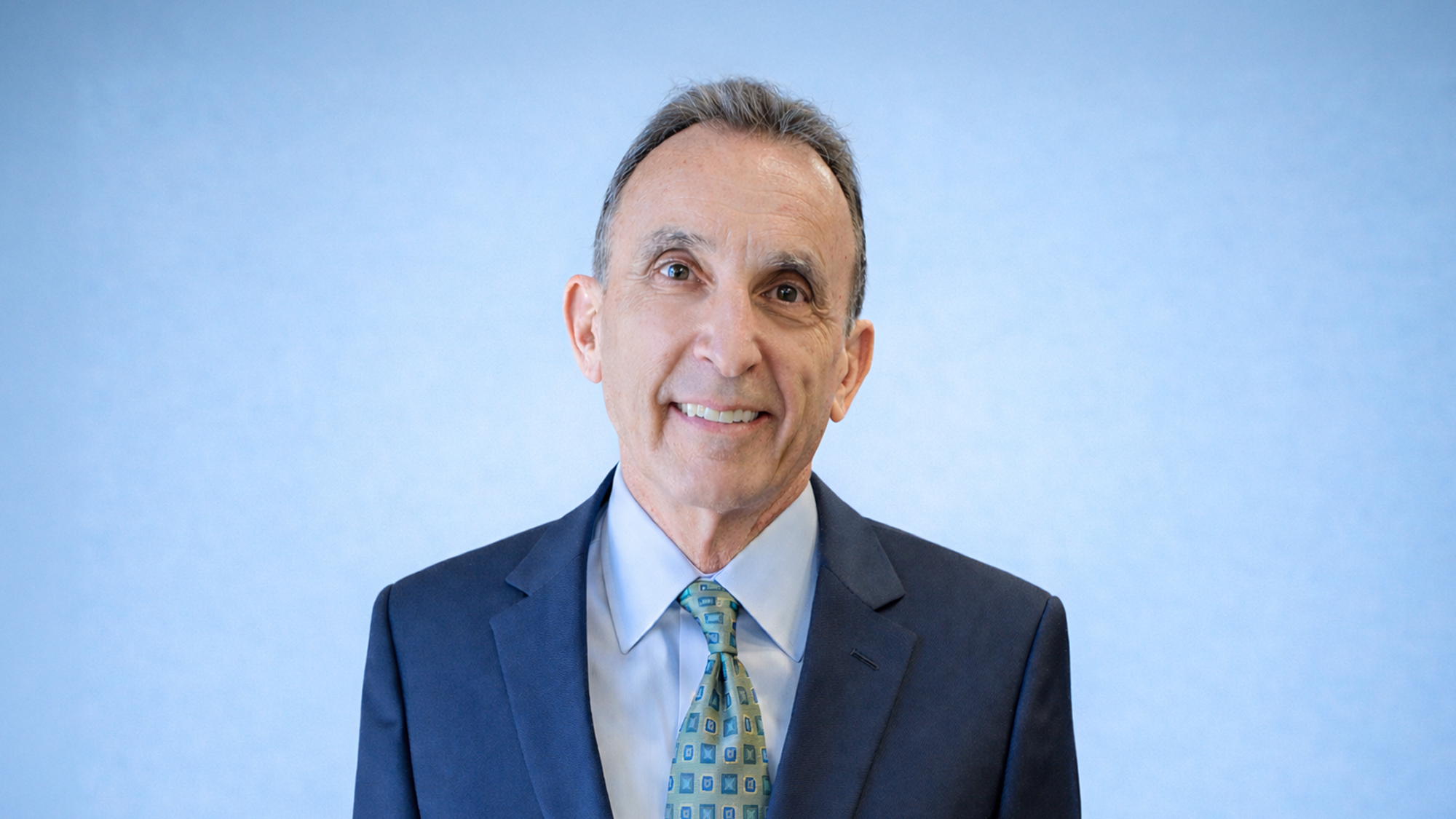 John Cassidy in suit against blue background