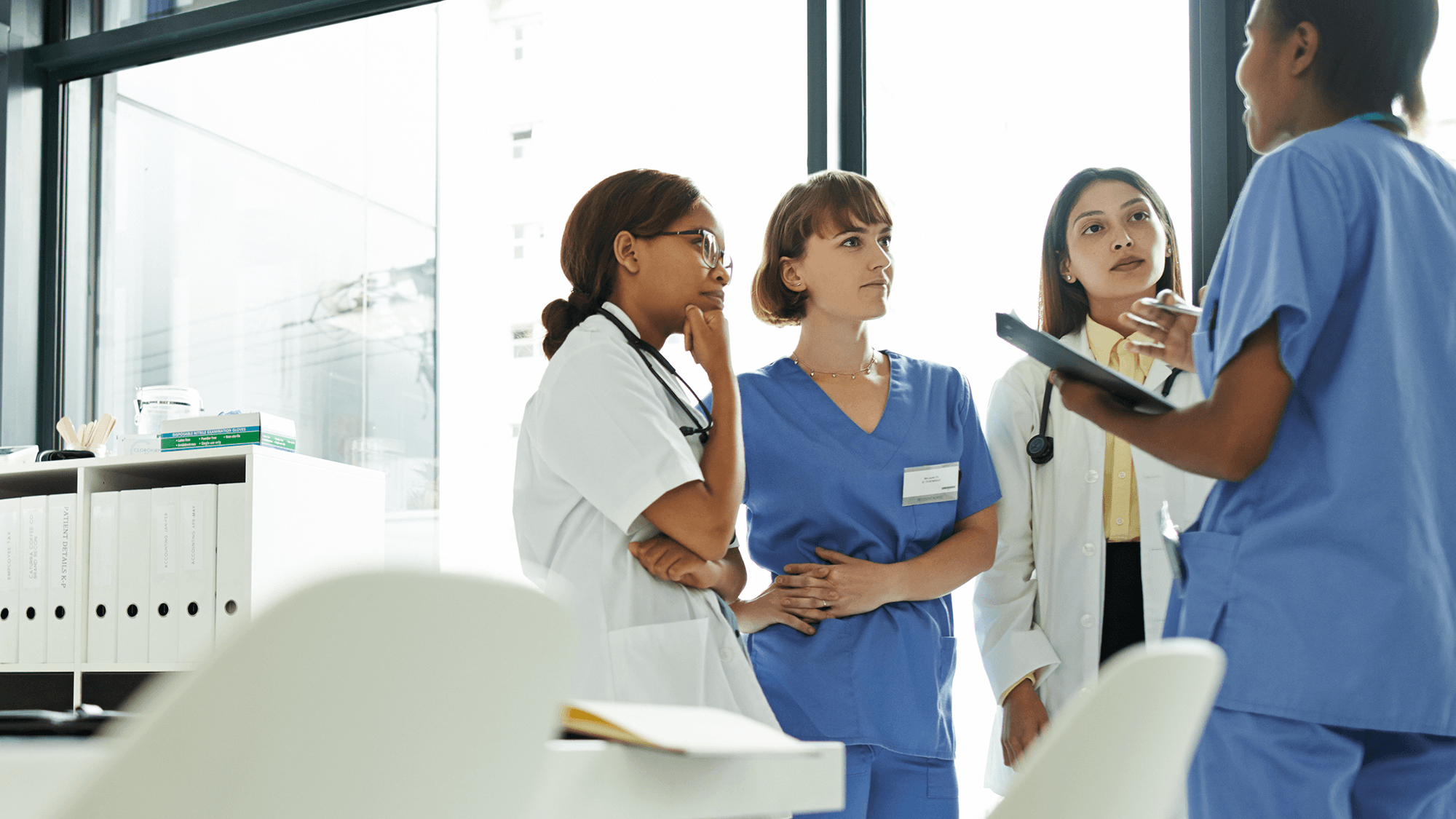 three clinicians getting an update for a doctor in a meeting room area
